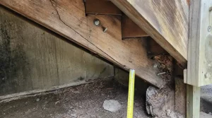 Close-up of a cracked and rotted stair stringer showing structural damage at the base, indicating the need for staircase remodeling